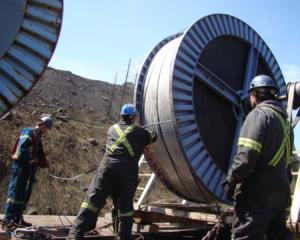 Belt Install Three workers working on preparing a conveyor belt roll