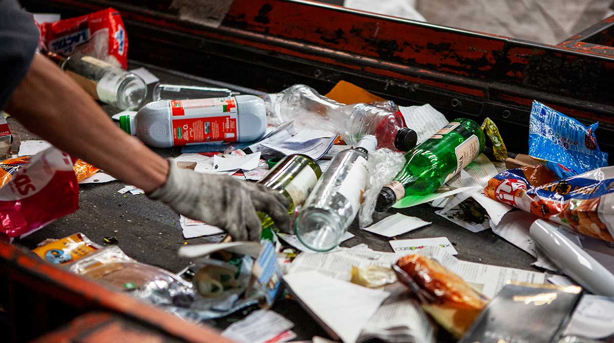 A conveyor belt is used to sort glass from paper at a recycling plant