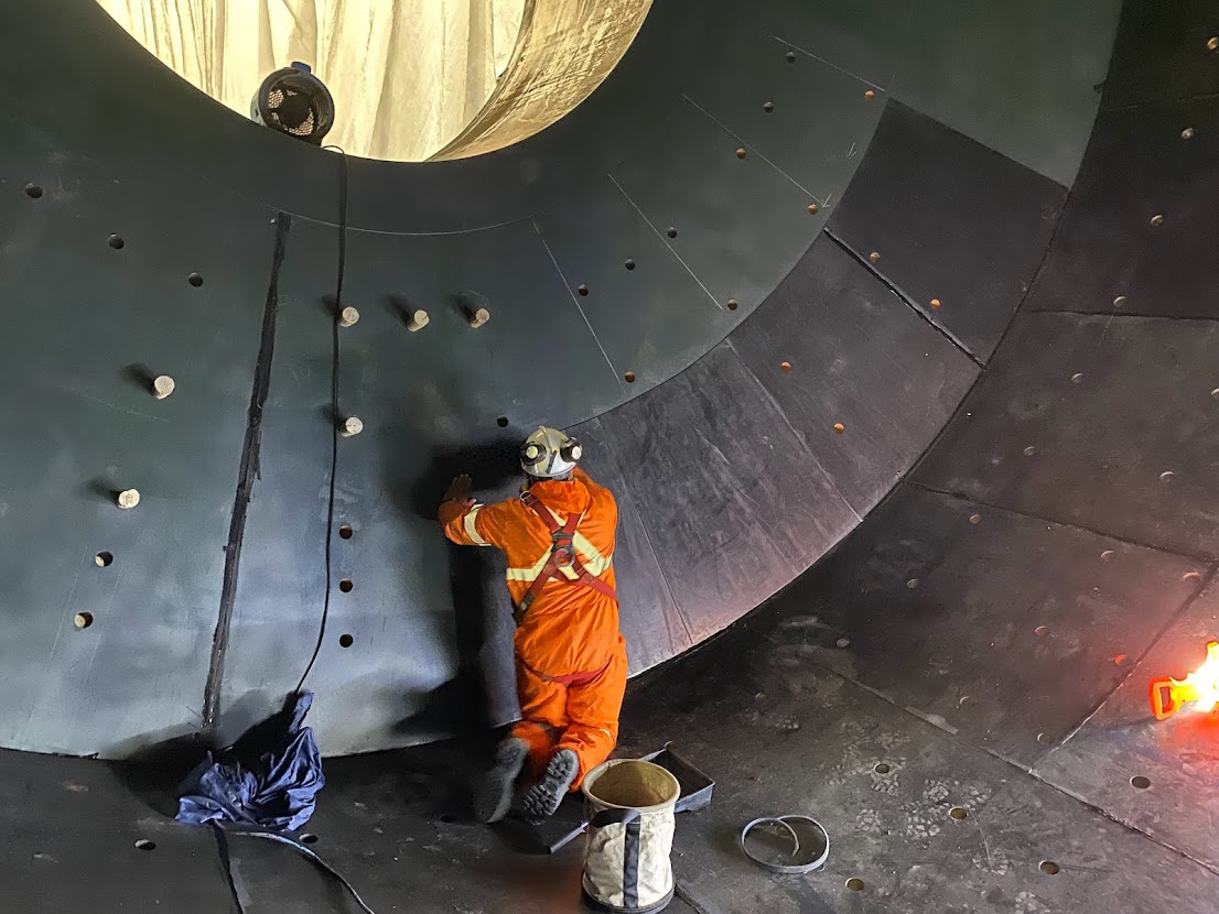 Two workers working on a conveyor belt roll