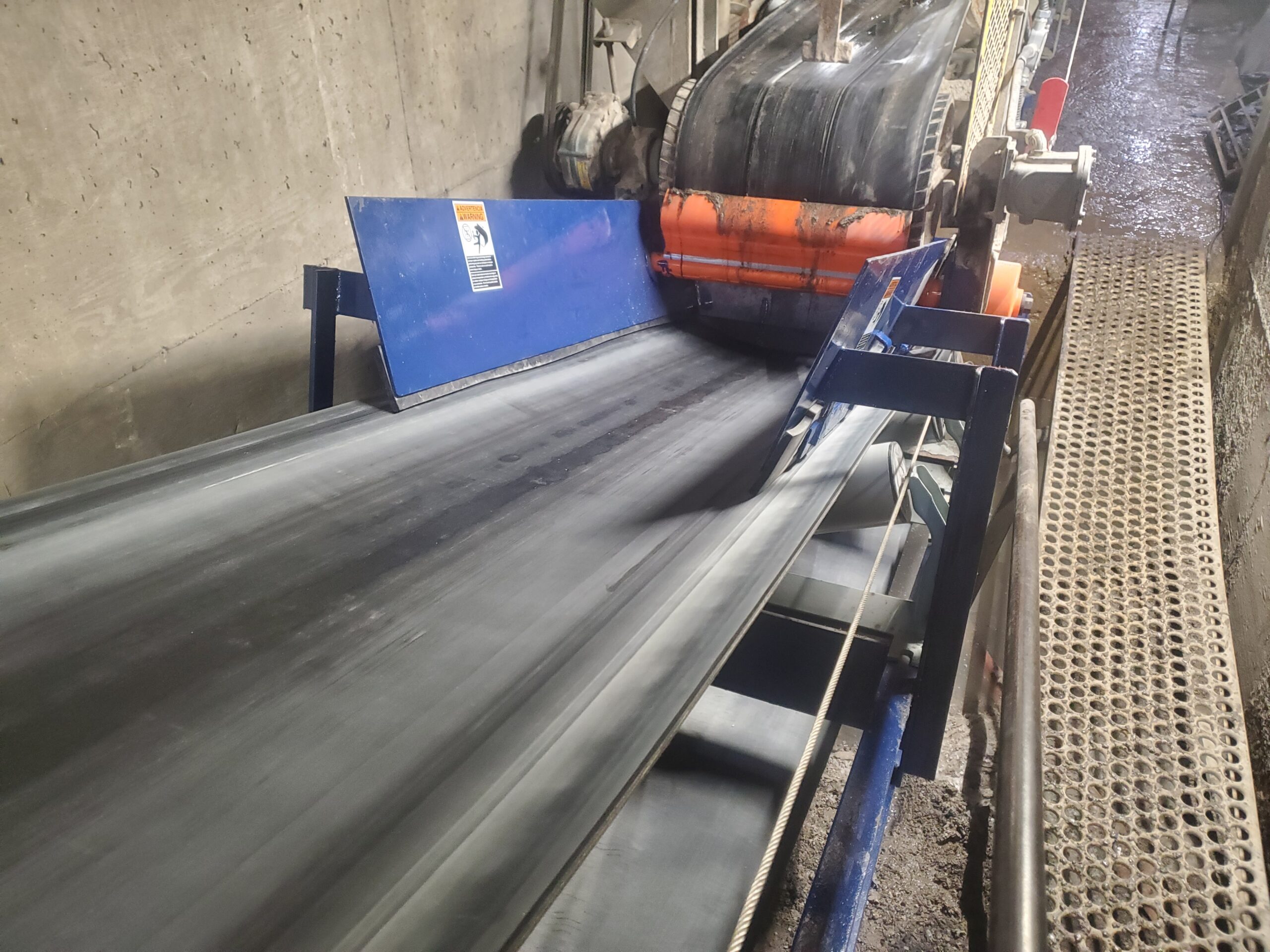Conveyor Belt cleaning blade Green Viacore background with a man supervising packages on a conveyor belt